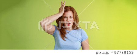 Ouch you kick my head. Frustrated concerned upset middle-aged redhead woman look shocked distressed touch temple complain kid shoot ball her face stand disappointed green background Ouch you kick my head. Frustrated concerned upset middle-aged redhead woman look shocked distressed touch temple complain kid shoot ball her face stand disappointed green background 97739155
