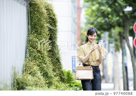 スマホ　若い女性　検索　調べる　笑顔　歩く 97740088
