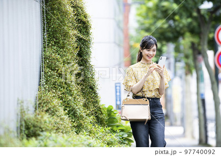 スマホ　若い女性　検索　調べる　笑顔　歩く 97740092