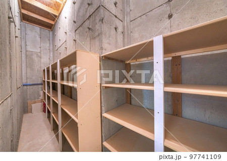 Unfinished narrow storage room with concrete walls and floors 97741109