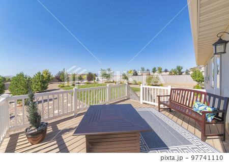Deck of a house with potted pine tree near the fire pit table and bench with carpet in the middle 97741110