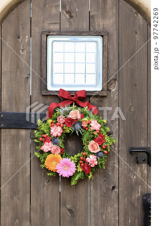 華やかなフラワーアレンジメント　アンティークな木製アーチ扉に飾られた花のリース　フラワーデザイナー 97742269