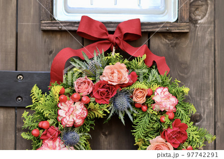 華やかなフラワーアレンジメント　アンティークな木製アーチ扉に飾られた花のリース　フラワーデザイナー 97742291