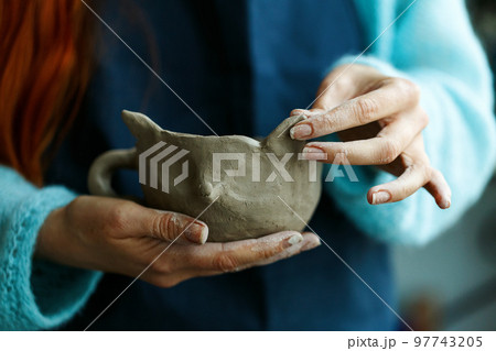 Woman potter in apron molding clay cup.Hands of professional ceramist create pottery crockery at workplace. Craftsmanship hobby.Small business with ceramics master classes education or handmade shop. 97743205