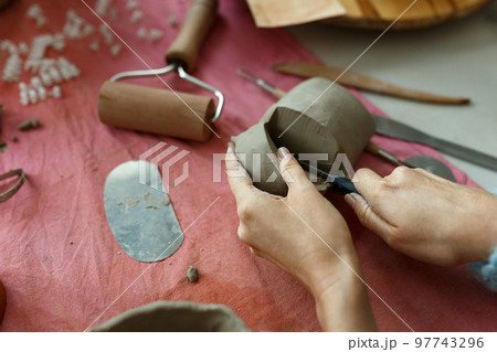 Adult potter master cutting the clay on table. Top view, closeup, hands only. Art and business, hobby and freelance working concept 97743296