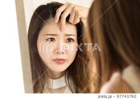 鏡で眉間のしわを見る女性。 97743762