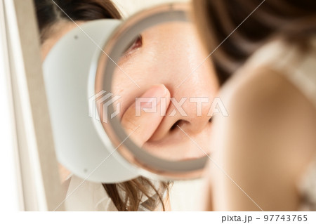 鏡で鼻を見る女性 97743765