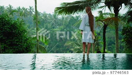 Long-haired girl enjoys the morning in rice terraces tropical forest nature background. Woman with thick and healthy hair. Summertime nature paddy field. Outdoor landscape. 97746563