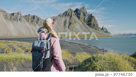 Morning scene of female traveler exploring Stokksnes cape with Vestrahorn in background Sunny summer day in Iceland 97746730