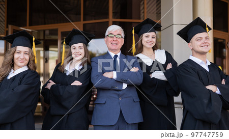 A professor and his students in graduation gowns stand with their arms crossed over their chests. 97747759