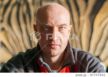 Close-up portrait of a bald man with blue eyes in a sports sweatshirt looks 97747942