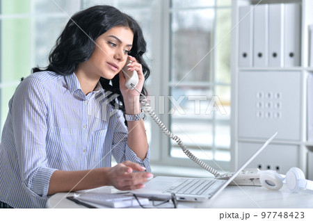 Portrait of a lyoung woman with phone working in office 97748423