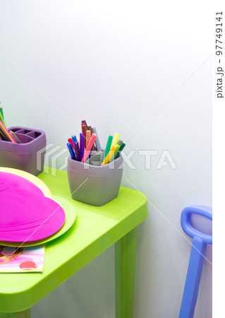 Children's table with pencils for drawing and toys in the nursery. Children's background is bright with copy space. Preschool education 97749141