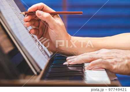 close up male musician hand writing a hit song while playing acoustic piano. songwriting concept close up male musician hand writing a hit song while playing acoustic piano. songwriting concept 97749421