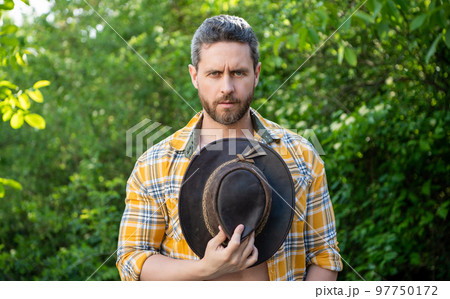 man hold cowboy hat. sexy cowboy in checkered shirt. western cowboy holding hat 97750172
