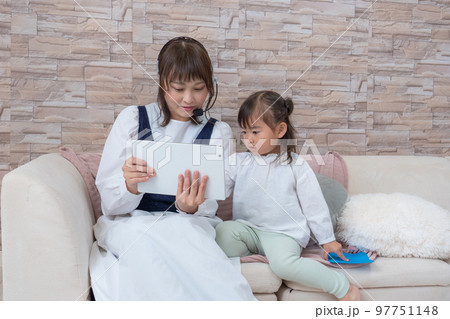 育児をしながらタブレットを操作する母親 97751148