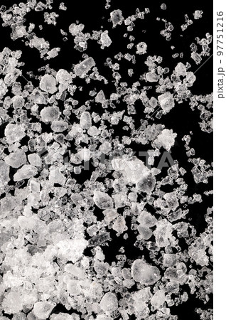 Sea salt, fleur de sel, close-up of crystals on a black surface. Also flor de sal, a salt that forms a thin, delicate crust on the sea water that evaporates. Finishing salt to flavor and garnish food. 97751216