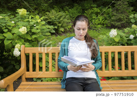 Outdoor portrait of a young woman with a book in the park Outdoor portrait of a young woman with a book in the park 97751910