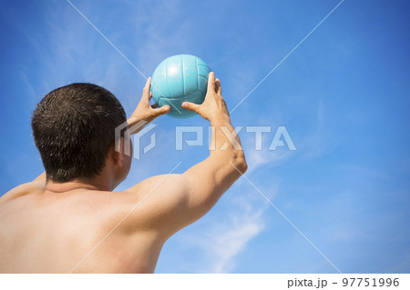 A man with a volleyball against the blue sky close-up. The concept of an active lifestyle A man with a volleyball against the blue sky close-up. The concept of an active lifestyle 97751996