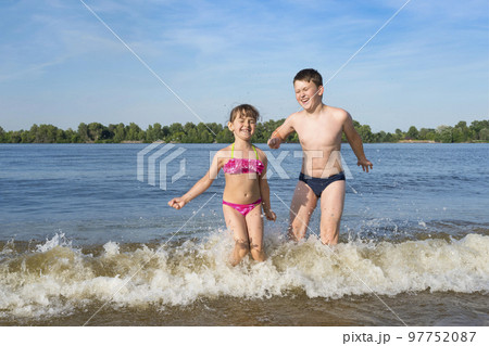 Happy children playing outdoors in the river. Beach season. The concept of a healthy lifestyle Happy children playing outdoors in the river. Beach season. The concept of a healthy lifestyle 97752087