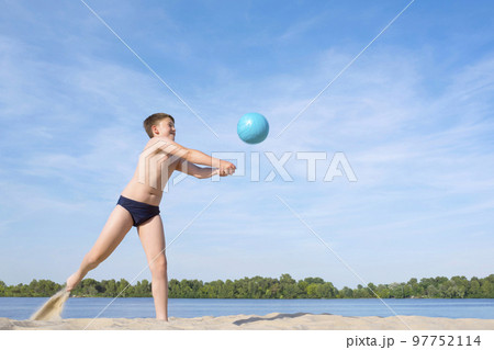 A teenager playing volleyball on the beach on a sunny day. Active lifestyle 97752114