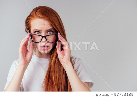 redhaired ginger woman wearing glasses and white cotton eco t-shirt in gray studio background redhaired ginger woman wearing glasses and white cotton eco t-shirt in gray studio background 97753139