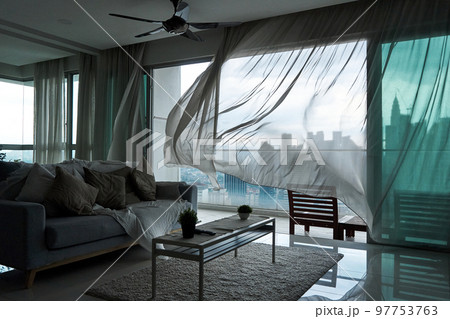 The wind rustles the curtain of the panoramic window with a cityscape The wind rustles the curtain of the panoramic window with a cityscape 97753763