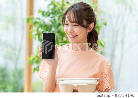 お弁当とスマホを持つ若い女性 97754140