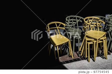 Detail of Stack of Dark green (Khaki color) and Yellow plastic chairs. Detail of Stack of Dark green (Khaki color) and Yellow plastic chairs. 97754545