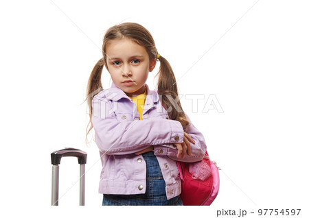 Caucasian pretty baby girl, preschooler child with two ponytails,dressed in purple jacket and blue denim overalls, posing with pink backpack and suitcase over white background. Travel Tourism concept Caucasian pretty baby girl, preschooler child with two ponytails,dressed in purple jacket and blue denim overalls, posing with pink backpack and suitcase over white background. Travel Tourism concept 97754597