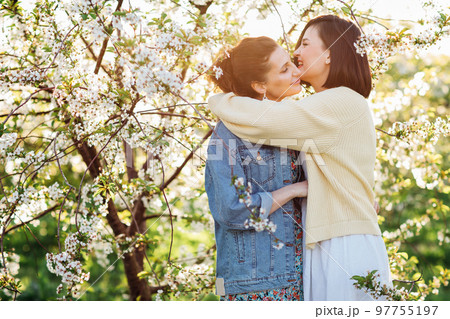 two attractive women hugging in a spring garden.  97755197