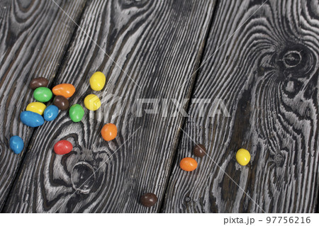 Chocolate candy in multi-colored glaze. Scattered on black pine boards. Chocolate candy in multi-colored glaze. Scattered on black pine boards. 97756216