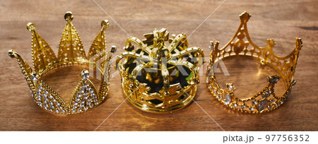 Happy Epiphany day. Three gold crowns on wooden background, symbol of Tres Reyes Magos, Three Wise Men.  97756352