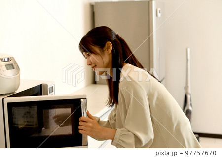 電子レンジを使う若いアジア人女性 97757670