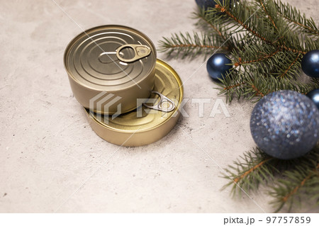 Christmas canned products, preservation, packed fish, meat or vegetables in can on concrete gray background with Christmas tree and toy balls. Copy space. New year food concept. Horizontal 97757859