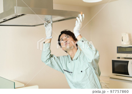 キッチンで換気扇を確認する男性作業員 97757860