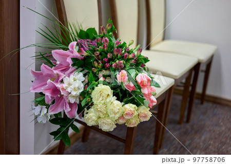 Big colourful flower bouquet on a white chair. Wedding day. 97758706