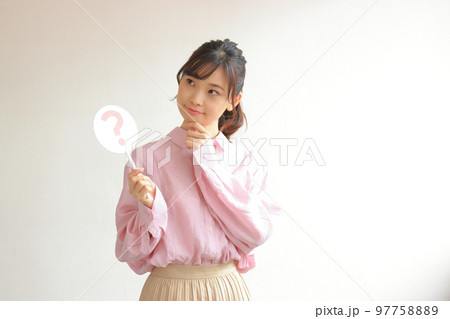 はてなのプレートを持ちあごに手を当てる若い女性1 97758889