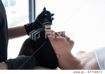 Woman on ultrasonic cleaning procedure. Hardware cosmetology. Woman on ultrasonic cleaning procedure. Hardware cosmetology. 97758972