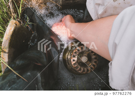 田んぼの水口で足を洗う農家 97762276
