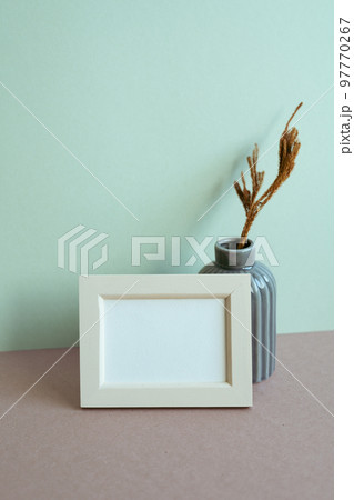 Blank picture frame and vase of dry plant on table. mint wall background. copy space Blank picture frame and vase of dry plant on table. mint wall background. copy space 97770267