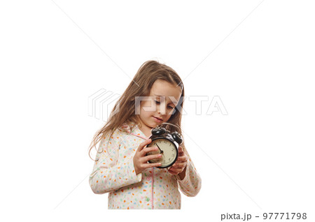 Caucasian beautiful sleepy little child girl with long hair,wearing trendy soft pajamas, setting the alarm clock before going to bed, isolated on white background with copy ad space. It's the bedtime Caucasian beautiful sleepy little child girl with long hair,wearing trendy soft pajamas, setting the alarm clock before going to bed, isolated on white background with copy ad space. It's the bedtime 97771798