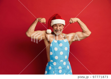 Senior Man Showing Biceps. Strong Bearded Man In Santa Hat And Apron Senior Man Showing Biceps. Strong Bearded Man In Santa Hat And Apron 97771873