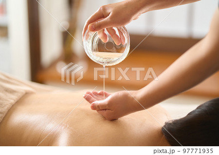 エステサロンでマッサージオイルを垂らすエステティシャン 97771935