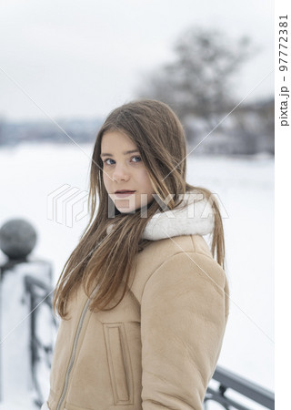 Winter portrait of pretty girl in fashionable beige sheepskin coat, white fur. Young woman in stylish outerwear on walk 97772381