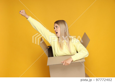 Concept of delivery and gift, young woman in box on yellow background Concept of delivery and gift, young woman in box on yellow background 97772402