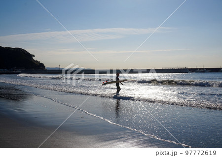 朝日を浴びるサーファー 97772619