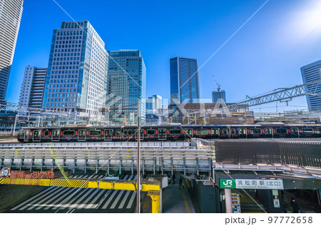日本の東京都市景観　浜松町駅を発車した黒い山手線(内回り）や超高層ビル群などを望む 97772658
