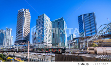 日本の東京都市景観　浜松町駅を発車した黒い山手線(内回り）や超高層ビル群などを望む 97772687