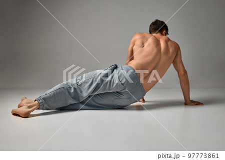 Back view photo of shirtless man in pants over grey studio background. Strong, relief, muscular body, back. Men's health and beauty Back view photo of shirtless man in pants over grey studio background. Strong, relief, muscular body, back. Men's health and beauty 97773861
